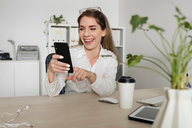 Vrouw die haar smartphone controleert op het werk