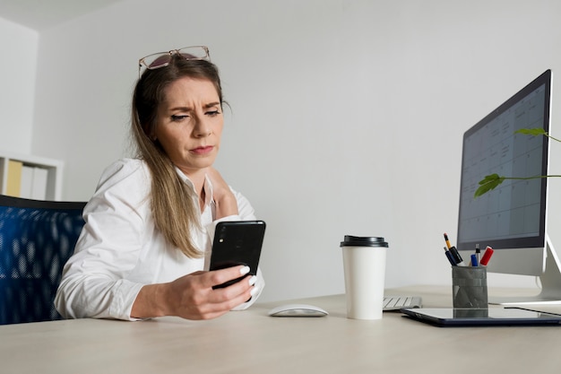 Vrouw die haar smartphone controleert op het werk