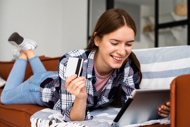 Vrouw die haar tablet bekijkt en een creditcard houdt