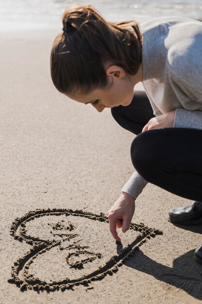 Vrouw die hart op nat zand maakt