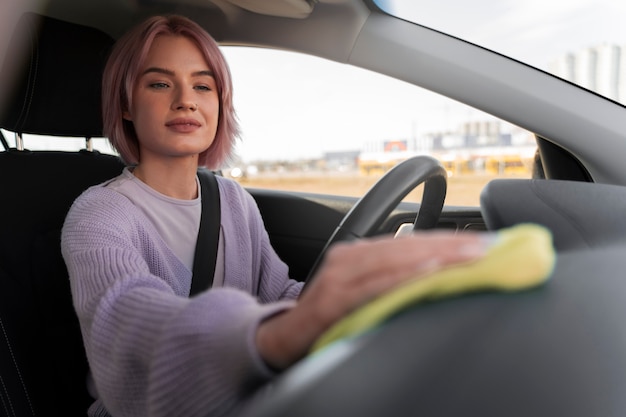 Gratis foto vrouw die het dashboard van haar auto schoonmaakt met een doek