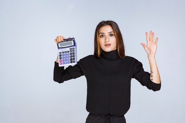 vrouw die het eindresultaat op de rekenmachine laat zien.