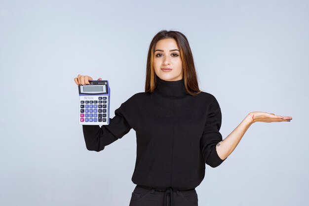 vrouw die het eindresultaat op de rekenmachine laat zien.