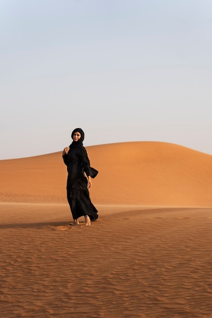 Gratis foto vrouw die hijab draagt in de woestijn