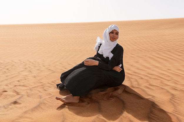 Gratis foto vrouw die hijab draagt in de woestijn