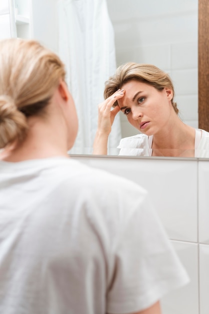 Vrouw die hoofdpijn heeft en de spiegel onderzoekt