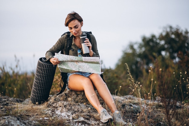 Vrouw die in berg met reiszak kaart bekijkt