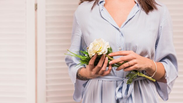 Vrouw die in blauwe kleding witte bloem houdt