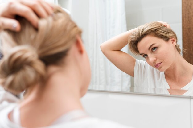 Vrouw die in de spiegel en het uitrekken kijkt