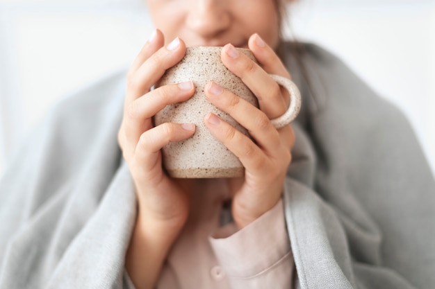 Gratis foto vrouw die in de winter een slokje thee uit de mok neemt