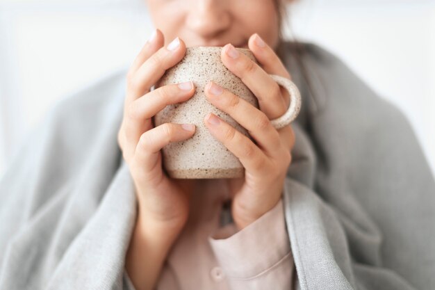 Vrouw die in de winter een slokje thee uit de mok neemt