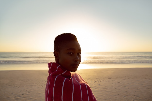 Vrouw die in deken wordt verpakt die zich op het strand bevindt