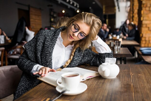 Vrouw die in glazen boek in koffie leest