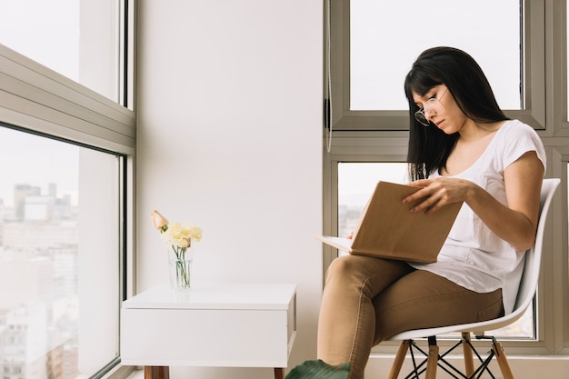 Vrouw die in glazen op stoel leest