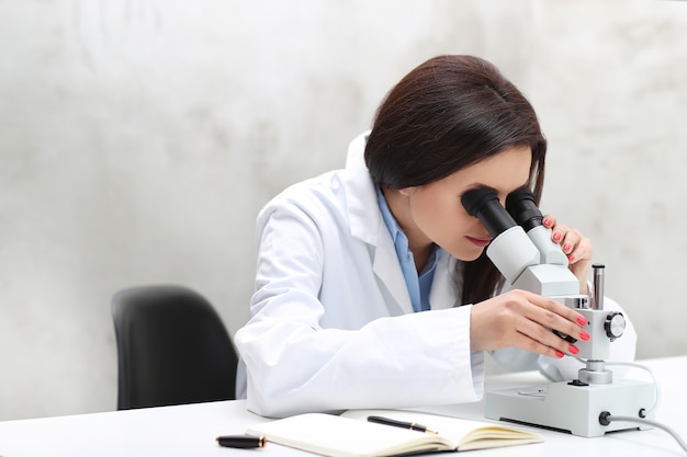 Vrouw die in het laboratorium met een microscoop werkt