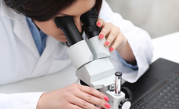 Vrouw die in het laboratorium met een microscoop werkt