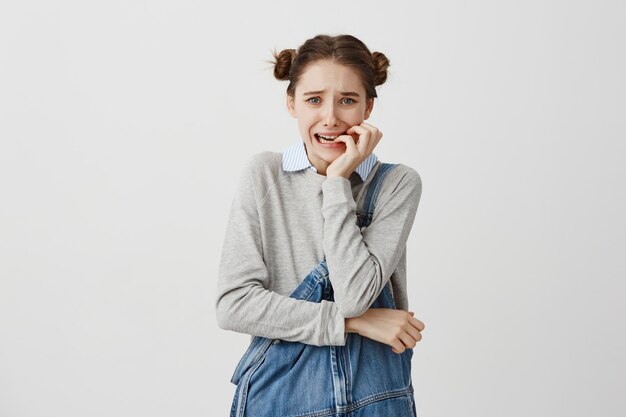 Vrouw die in jeans jumpsuit haar spijkers bijt die angst voelt die in spanning kijkt. Vrouwelijke zakelijke beginner door moeilijkheden die zich zorgen maken over haar falen. Menselijke emoties