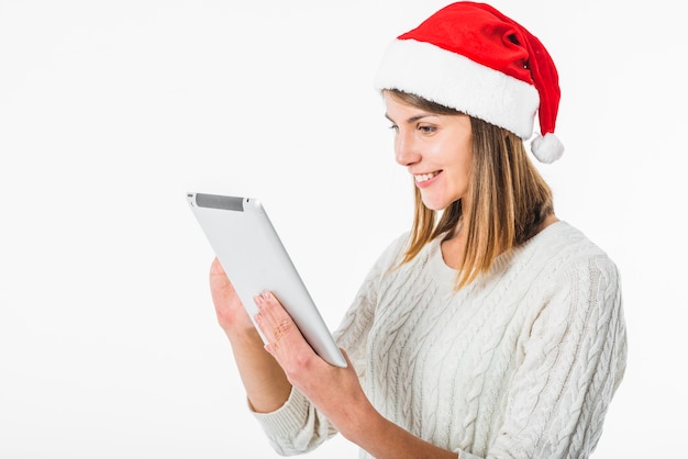 Vrouw die in Kerstmanhoed tablet bekijkt