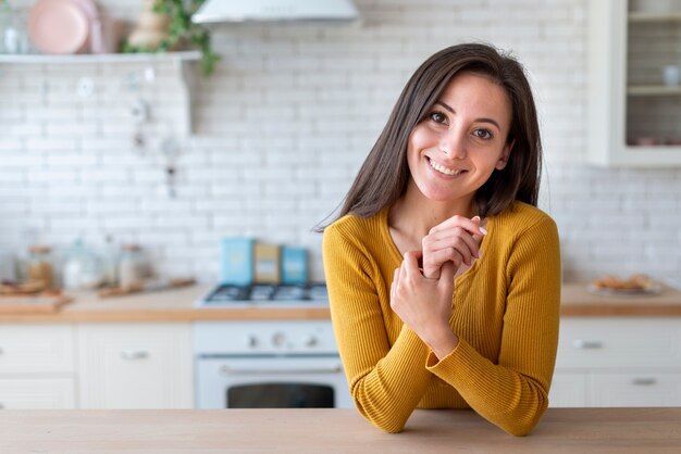 Vrouw die in keuken de camera bekijkt