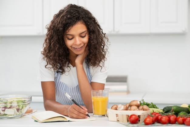 Vrouw die in notitieboekje in keuken schrijft