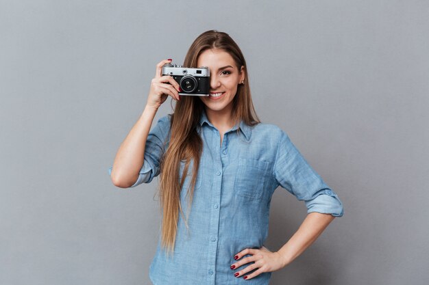Vrouw die in overhemd foto op retro camera maakt
