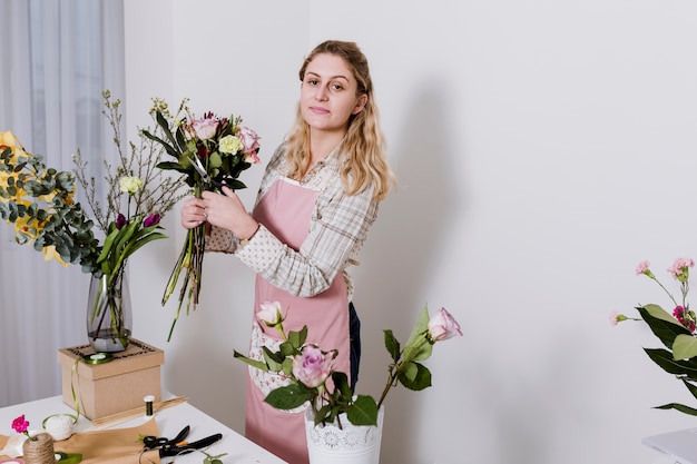 Vrouw die in schort bloemen in winkel voorbereidt