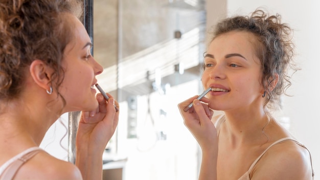 Vrouw die in spiegel kijkt en lippenstift toepast