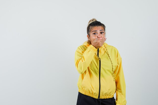 Vrouw die in sportkostuum hand op mond houdt en bang, vooraanzicht kijkt.