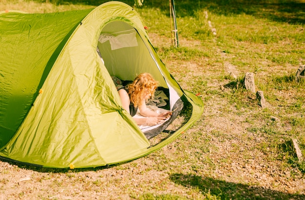 Gratis foto vrouw die in tent met tablet ligt