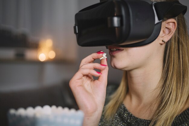 Vrouw die in VR-hoofdtelefoon popcorn eet