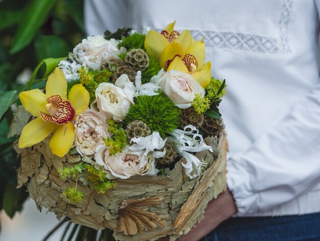 Vrouw die in wit overhemd bleke kleuren van bloemen in document boeket houdt