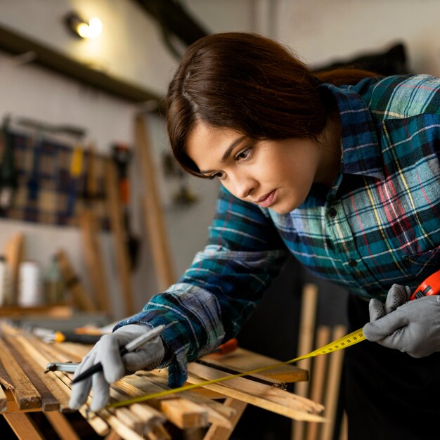 Vrouw die in workshop werkt die houten planken meet