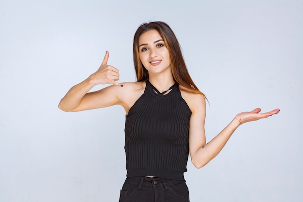 Vrouw die in zwart overhemd positief handteken maakt.