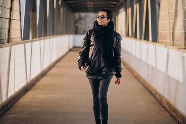 Vrouw die in zwarte jas door de brug loopt