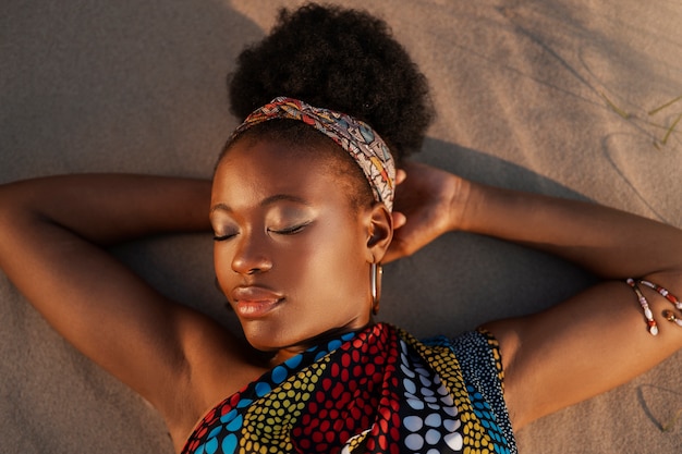 Gratis foto vrouw die inheemse afrikaanse kleding draagt bij het strand