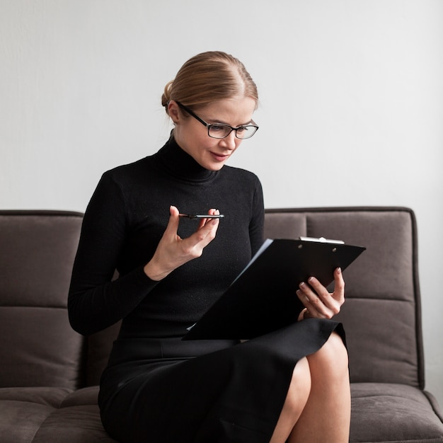 Vrouw die klembord bekijkt en mobiel houdt