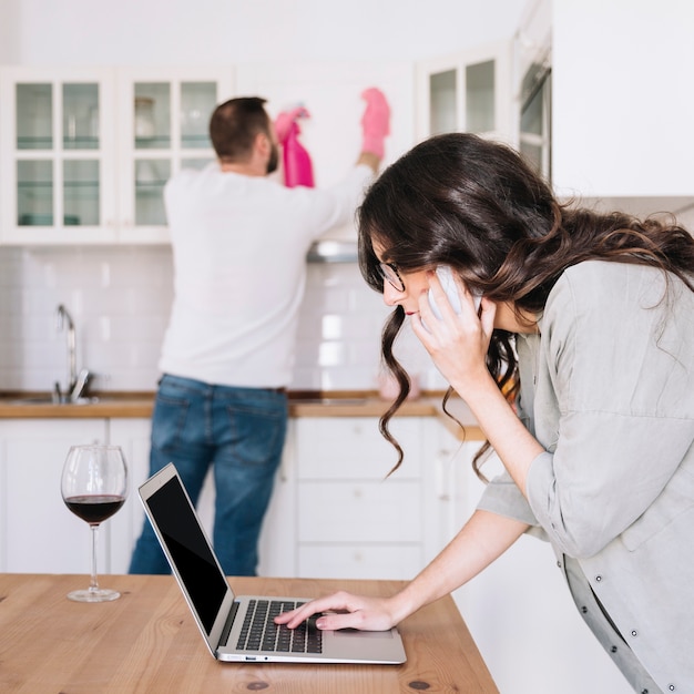 Vrouw die laptop met behulp van terwijl mens het schoonmaken