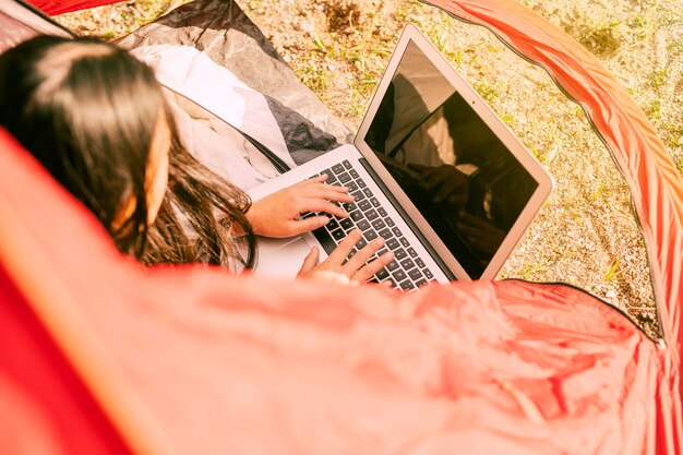 Vrouw die laptop met behulp van terwijl rustend in het kamperen