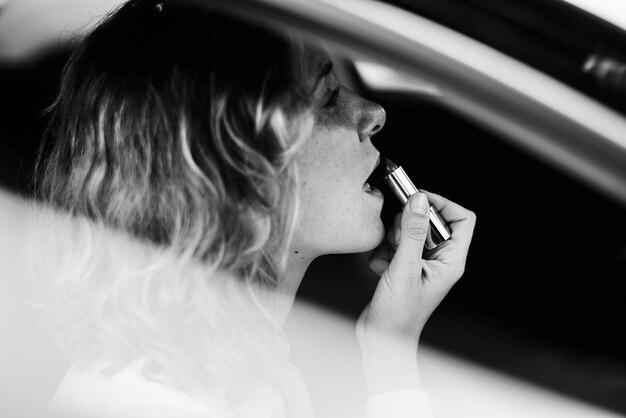 Vrouw die lippenstift opdoet in een auto