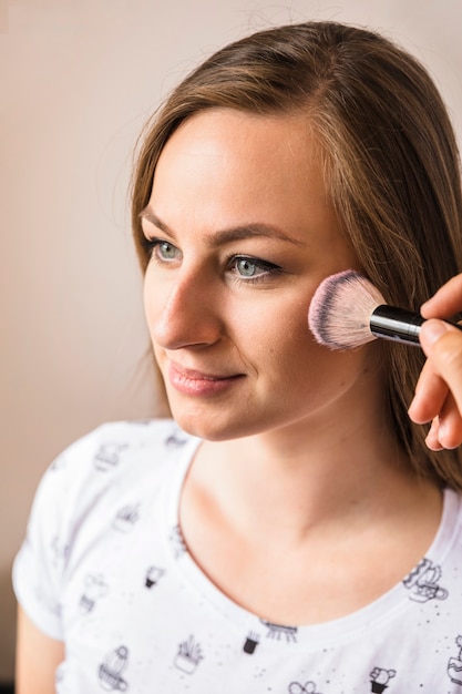 Vrouw die make-up op haar gezicht toepast