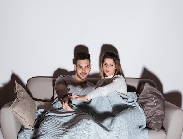 Vrouw die man met verre TV tegenhouden om kanaal op TV op bank te veranderen