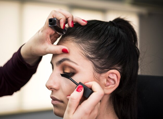 Vrouw die mascara op model toepast