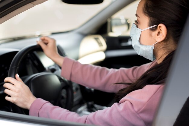 Vrouw die masker binnen haar eigen auto draagt