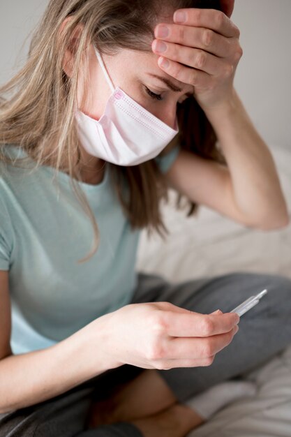 Vrouw die masker draagt dat binnen haar temperatuur controleert