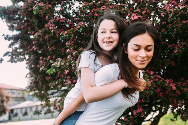 Vrouw die meisje en boom op de achtergrond draagt