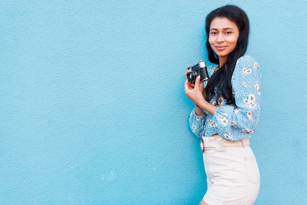 Gratis foto vrouw die met bloemenblouse een camera houdt