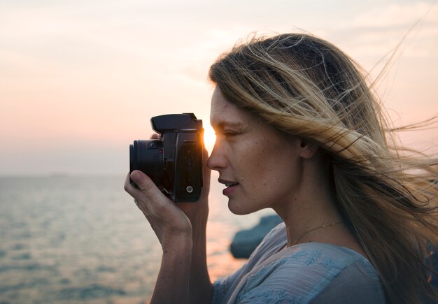 Vrouw die met camera op het strand schieten