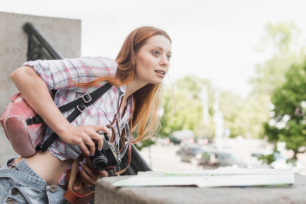 Gratis foto vrouw die met camera stad van aantrekkelijkheden geniet