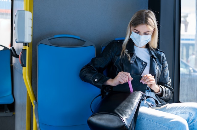 Vrouw die met de openbare bus reist en een medisch masker draagt voor bescherming