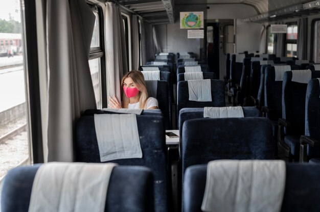 Vrouw die met de trein reist en een medisch masker draagt voor bescherming